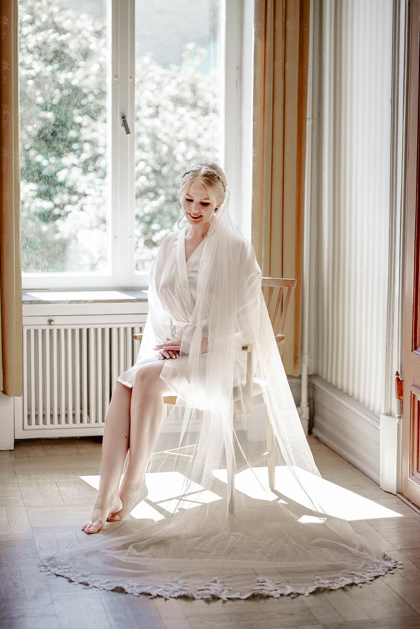 Bröllopsfotografering under förberedelserna. Brud i vacker satin morgonrock